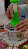 Hand using a green and silver manual juicer on a tiled surface.